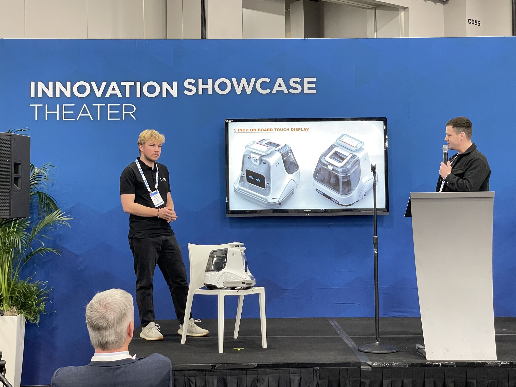 two men on stage presenting the X1000 robot at the innovation showcase theater at a tradeshow
