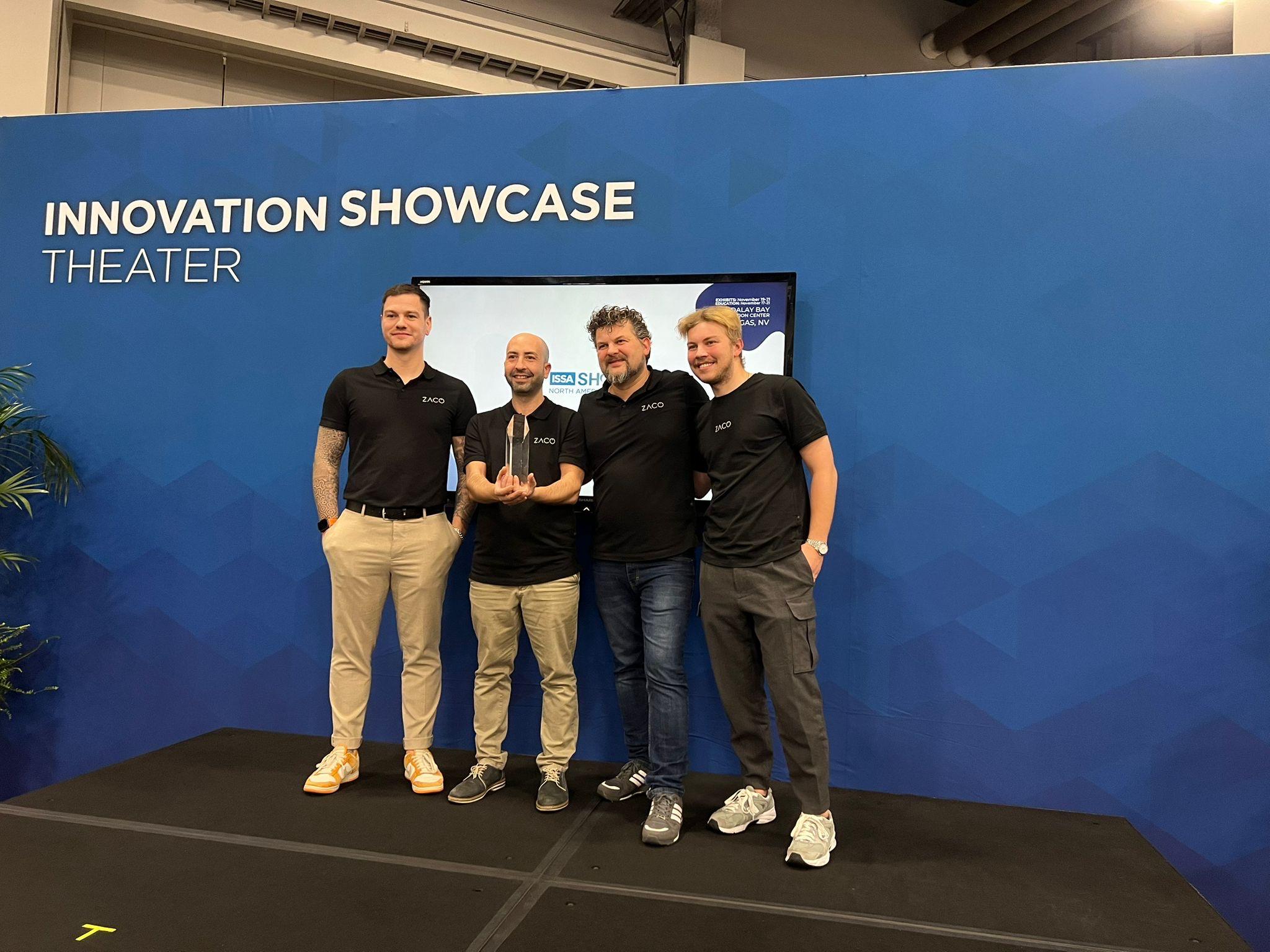four men standing on stage holding an award